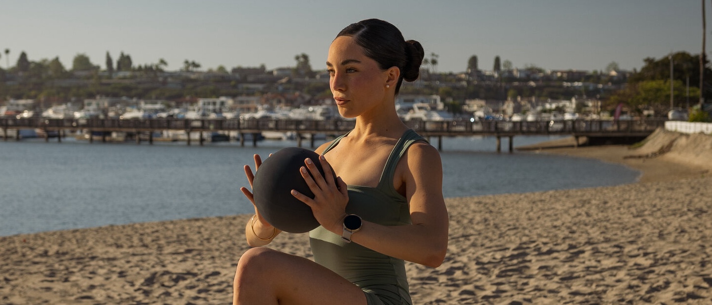 Marianne Hanson holding a Pilates ball on the beach in Newport Beach